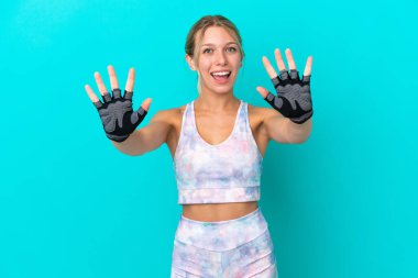 Beyaz kadın, mavi arka planda izole edilmiş. Parmaklarıyla 10 kişi sayıyor.