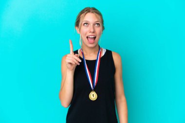 Mavi arka planda madalyaları olan genç, beyaz bir kadın parmağını kaldırarak çözümü bulmaya çalışıyor.
