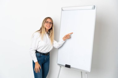 Young blonde woman isolated on white background giving a presentation on white board and writing in it clipart