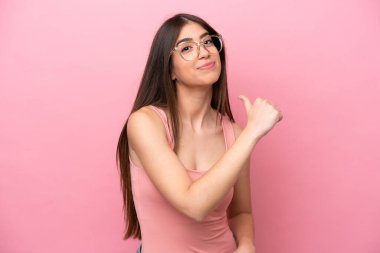 Genç beyaz kadın pembe arka planda soyutlanmış gururlu ve kendini beğenmiş.