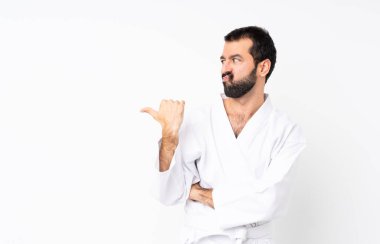 İzole edilmiş beyaz arka planda karate yapan genç adam mutsuz ve kenarı işaret ediyor.