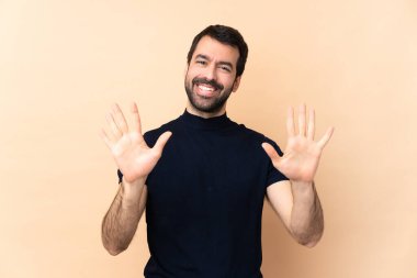 Kafkasyalı yakışıklı adam tecrit edilmiş arka planda parmaklarıyla 10 kişi sayıyor.