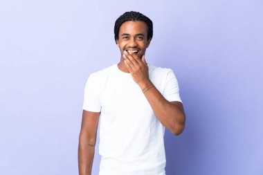Örgülü genç Afrikalı Amerikalı adam mor arka planda izole edilmiş mutlu ve gülümseyen elleriyle ağzını kapatıyor.