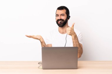 Tele pazarlamacı beyaz bir adam kulaklıkla çalışıyor ve fotokopi makinesini avucunun içinde tutuyor..