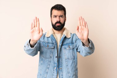 İzole edilmiş arka planda sakallı beyaz bir adam dur hareketi yapıyor ve hayal kırıklığına uğruyor.