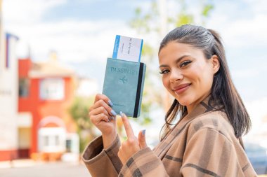 Genç ve güzel bir kadın dışarıda pasaportunu tutuyor ve onu gösteriyor.