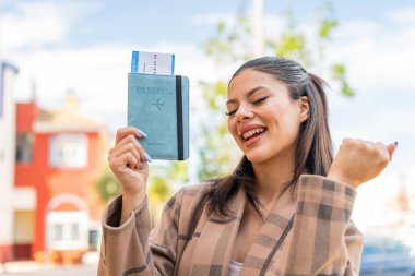 Dışarıda elinde pasaport tutan genç ve güzel bir kadın zaferi kutluyor.