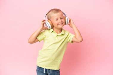 Küçük Rus çocuk pembe arka planda izole edilmiş müzik ve dans dinliyor.