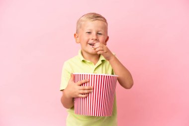 Küçük Rus çocuk izole bir arka planda büyük bir kasede patlamış mısır yiyor.