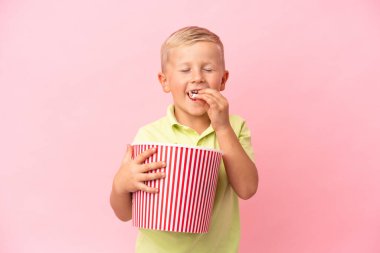 Küçük Rus çocuk izole bir arka planda büyük bir kasede patlamış mısır yiyor.