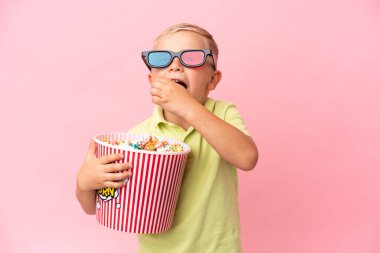 Küçük Rus çocuk izole bir arka planda büyük bir kasede patlamış mısır yiyor.