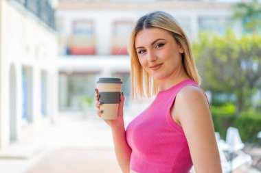 Açık havada gülümseyen güzel sarışın bir kadın.