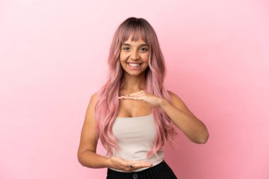 Pembe saçlı melez bir kadın. Pembe arka planda izole edilmiş. Fotokopi alanı hayali bir şey tutuyor.