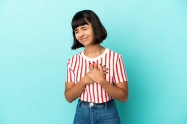 Mavi arka planda soyutlanmış genç melez bir kadın. Kalbi ağrıyor.