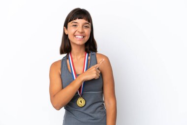 Young mixed race woman with medals isolated on white background pointing to the side to present a product