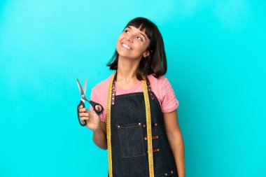 Young mixed race seasmtress woman isolated on blue background thinking an idea while looking up