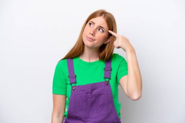 Genç kızıl saçlı kadın beyaz arka planda izole edilmiş. Delilik hareketi yapıyor. Parmağını kafasına koyuyor.