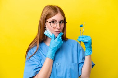 Genç kızıl saçlı dişçi kadın sarı arka planda izole edilmiş.