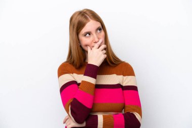 Beyaz arka planda izole edilmiş genç kızıl saçlı kadının şüpheleri var ve kafası karışmış bir yüz ifadesi var.