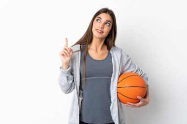 Beyaz arka planda izole edilmiş basketbol oynayan genç bir kadın harika bir fikre işaret ediyor.