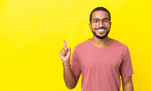 Young latin man isolated on yellow background pointing up a great idea
