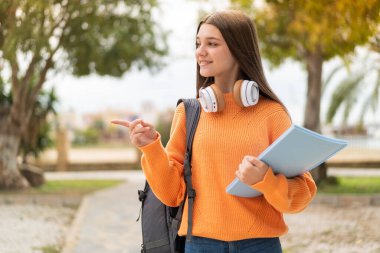 Tecrit edilmiş bir geçmişi olan genç kız bir ürünü sunmak için kenarı işaret ediyor.