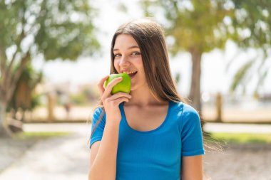 Dışarıdaki genç kız elma yiyor.