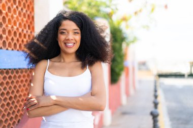 Genç Afrikalı Amerikalı kadın açık havada kollarını ön cephede çapraz tutuyor.