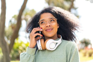 Açık havada cep telefonu kullanan genç Afrikalı Amerikalı kadın.