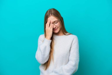 Mavi arka planda başağrısı olan genç bir Rus kadın.