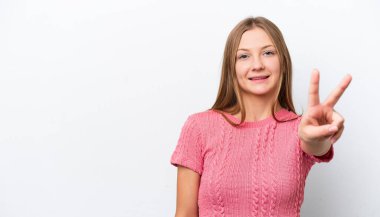 Beyaz arka planda izole edilmiş genç Rus kadın gülümsüyor ve zafer işareti gösteriyor.