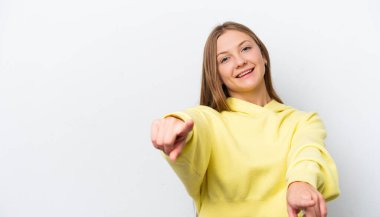 Beyaz arka planda izole edilmiş genç bir Rus kadını mutlu bir ifadeyle ön tarafı işaret ediyor.