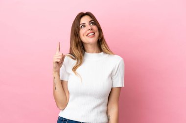 Pembe arka planda izole edilmiş beyaz kadın yukarı bakıyor ve şaşırıyor.