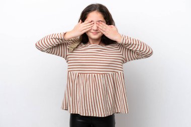 Beyaz arka planda izole edilmiş küçük bir kız gözleri elleriyle kaplıyor ve gülümsüyor.