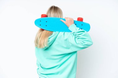 Beyaz arka planda izole edilmiş beyaz tenli genç bir kadın, arka planda kaykay yapıyor.