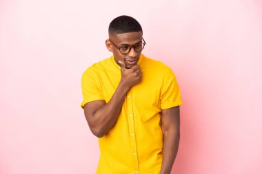 Pembe arka planda izole edilmiş genç latin adam yan tarafa bakıyor.