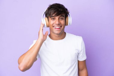 Mor arka planda izole edilmiş genç beyaz adam müzik dinliyor.