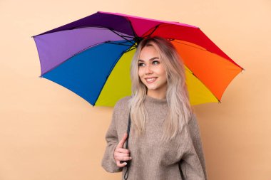 Arka planda şemsiye tutan genç bir kız gülüyor ve yukarı bakıyor.