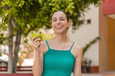 Elmalı ve mutlu genç bir kadın açık havada.