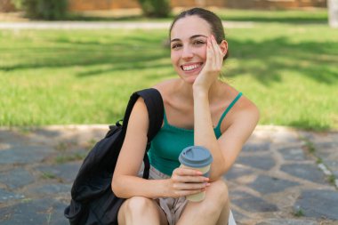 Dışarıdaki güzel kadın elinde kahve tutuyor.