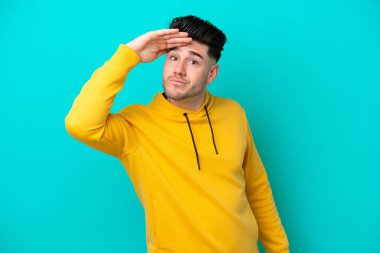 Kafkasyalı genç bir adam mavi arka planda izole edilmiş. Bir şeye bakmak için uzaklara bakıyor.