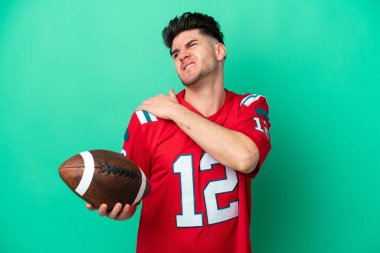 Rugby oynayan Kafkasyalı genç adam, yeşil arka planda izole edilmiş, omuz ağrısından muzdarip.