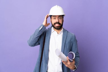 Miğferli genç bir mimar, elinde mor arkaplandan izole edilmiş planlar tutuyor.