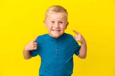 Sarı arka planda izole edilmiş küçük bir Rus çocuğu baş parmak işareti yapıyor.