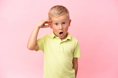 Pembe arka planda izole edilmiş küçük Rus çocuk çözümü bulmaya çalışıyor.