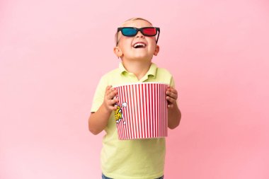 Küçük Rus çocuk izole bir arka planda büyük bir kasede patlamış mısır yiyor.