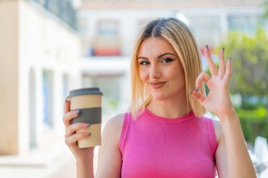 Dışarıdaki güzel sarışın kadın parmaklarıyla işaret veriyor.