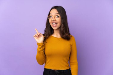 Mor arka planda izole edilmiş genç melez kadın parmağını kaldırarak çözümü bulmaya çalışıyor.