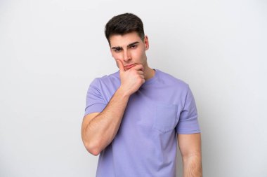 Beyaz arka planda soyutlanmış genç beyaz bir adamın şüpheleri var.