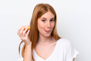 Beyaz arka planda izole edilmiş genç kızıl saçlı kadın elinde donut tutuyordu.